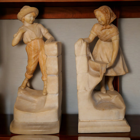 Pair of Circa 1925 Italian Art Deco Enrico Brunelleschi Carved Two-Tone Alabaster Figural Young Boy and Girl by Stone Wall Bookends